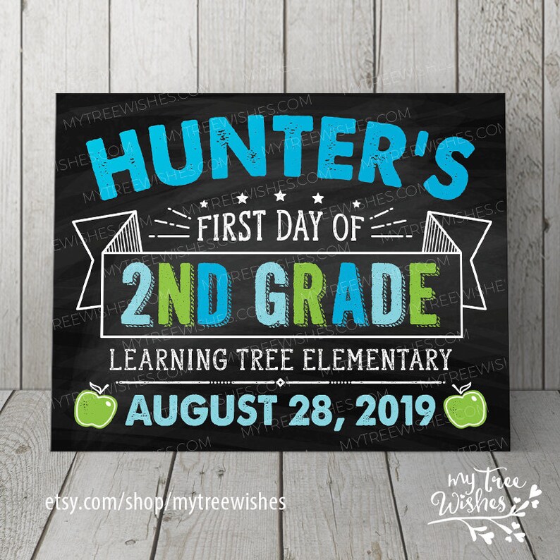 May include: A chalkboard-style sign with the text "Hunter's First Day of 2nd Grade." The sign includes the school name, date, and apple graphics. The background is black with white text and blue and green accents.