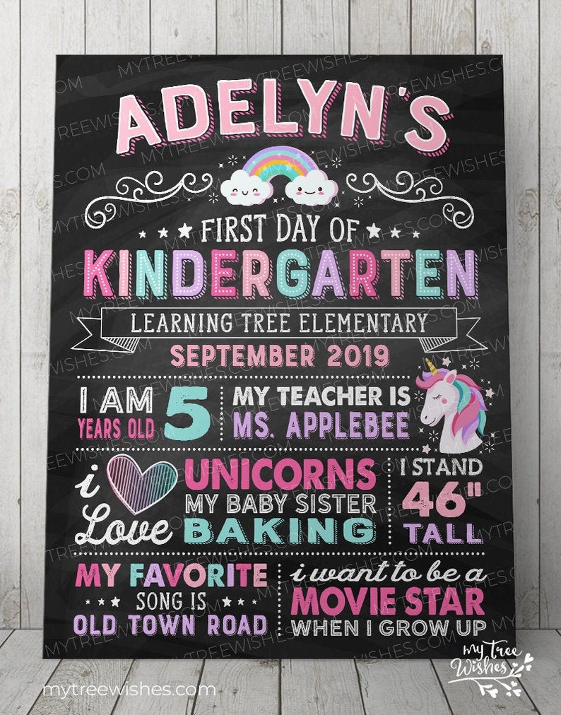 May include: A chalkboard-style sign with the text "Adelyn's First Day of Kindergarten." It includes a rainbow, unicorn, and details like age, teacher's name, and favorite things. The sign is 46 inches tall.