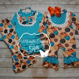 May include: Two-piece and one-piece outfits with a pumpkin pattern. The outfits feature turquoise and white polka dot tops with lace trim and ruffles. The pants and jumpsuit have a pumpkin print in orange, black, and blue.