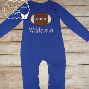 May include: Blue long-sleeved baby onesie with a white football graphic and the text "Wildcats" embroidered on the front.