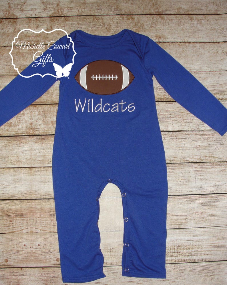 May include: Blue long-sleeved baby onesie with a white football graphic and the text "Wildcats" embroidered on the front.