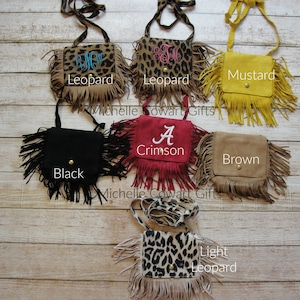 May include: Seven different colors of small fringed purses with a variety of designs. The purses are made of suede and have a long strap. The colors include black, brown, mustard, crimson, and leopard print.