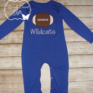 May include: Blue long-sleeved baby onesie with a white football graphic and the text "Wildcats" embroidered on the front.