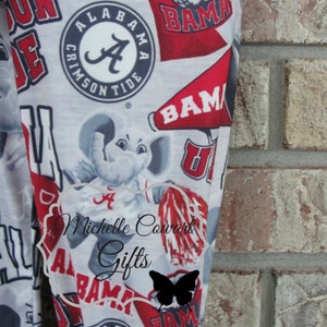 May include: Leggings with a repeating pattern of Alabama Crimson Tide logos, including the team's elephant mascot, the word "BAMA", and the "A" logo. The leggings are primarily white with red and black accents.