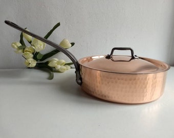 May include: A copper pot with a hammered finish and a lid. The pot has a long, silver handle.