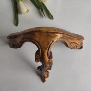 French vintage wooden small wall hanging shelf with gold painted finish, circa mid century.