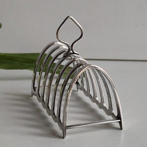 Rejilla para tostadas pequeña vintage plateada con asa superior y sellos.