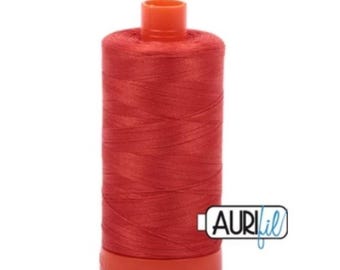 May include: A spool of red thread with a matching red base and top. The thread is tightly wound, and the spool has the brand name "AURIfil" printed on it. This thread is likely used for sewing, quilting, or other textile crafts.