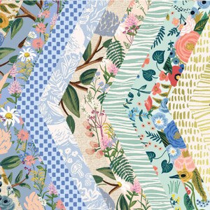 May include: A collection of patterned paper sheets with floral and botanical designs. The papers feature a variety of colors, including pink, blue, green, and yellow. The text "RIFLE PAPER CO." and "Wildwood" are displayed in the upper left corner.