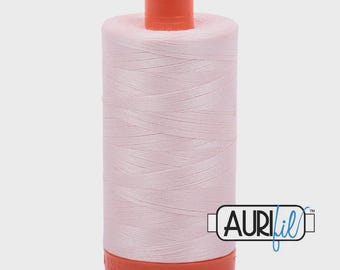 May include: A spool of light pink thread with an orange top and base. The thread is tightly wound, and the spool has the Aurifil logo on the side. This thread is likely used for sewing, quilting, or embroidery projects.