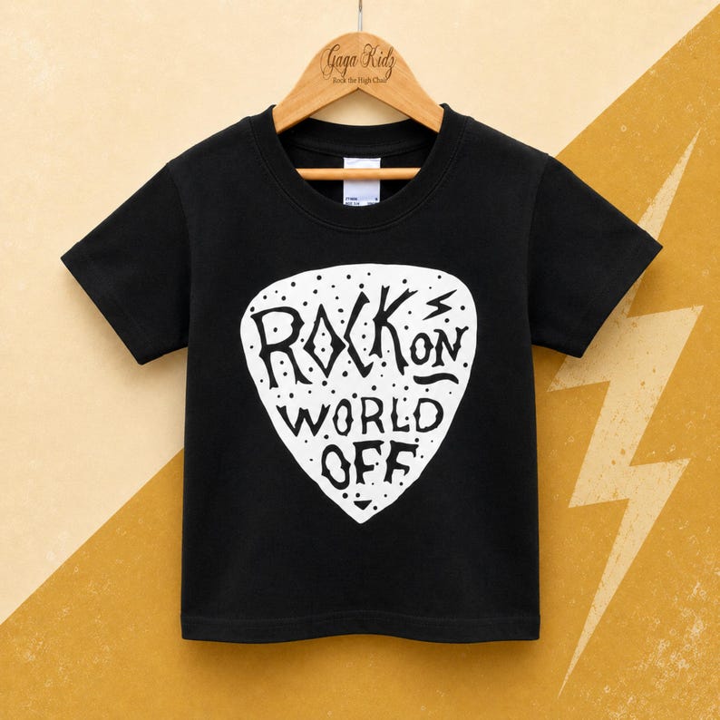May include: A black short-sleeved t-shirt featuring a large white guitar pick graphic on the front. The graphic contains the text "ROCK ON WORLD OFF" in a stylized font, surrounded by small dots. The shirt is displayed on a wooden hanger.