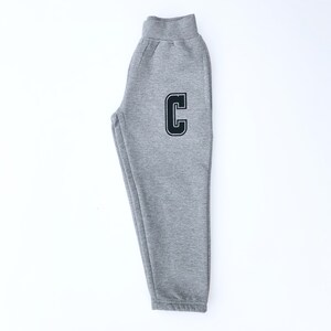 May include: Gray sweatpants with a black letter C on the left leg.