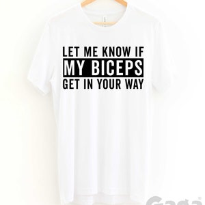 May include: White t-shirt with black text that reads "Let me know if my biceps get in your way".