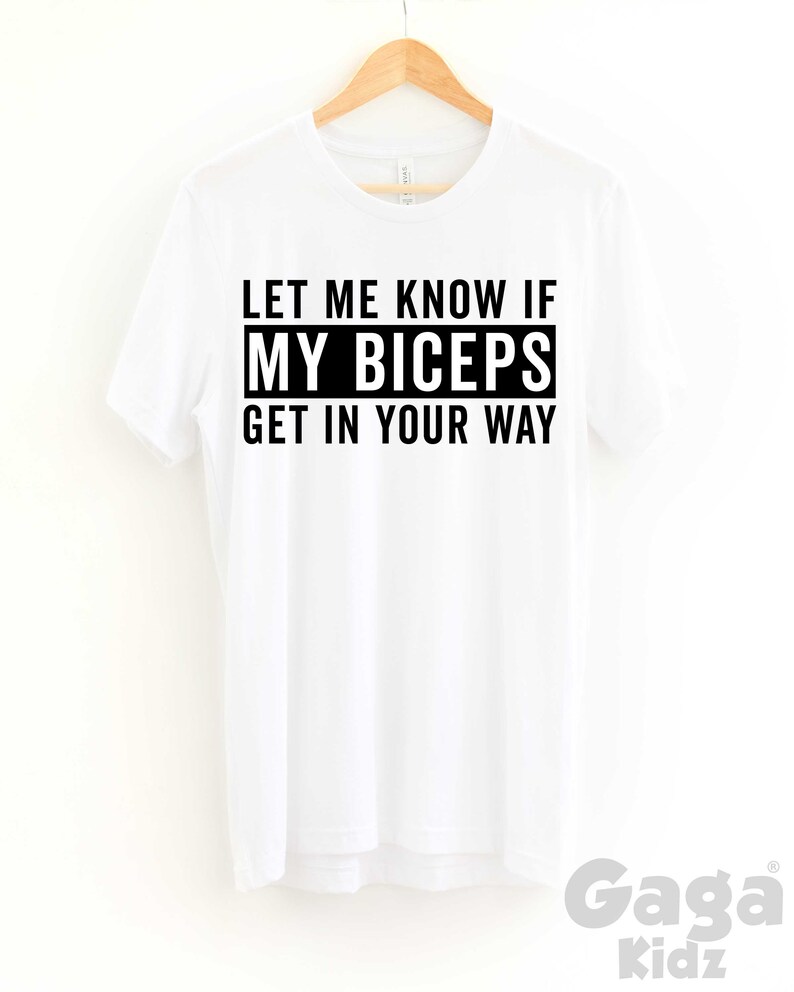May include: White t-shirt with black text that reads "Let me know if my biceps get in your way".