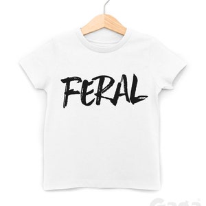 Op de afbeelding: Wit T-shirt met zwarte, penseelstreekachtige tekst "FERAL".