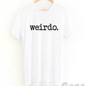 May include: White t-shirt with black text that reads "weirdo."