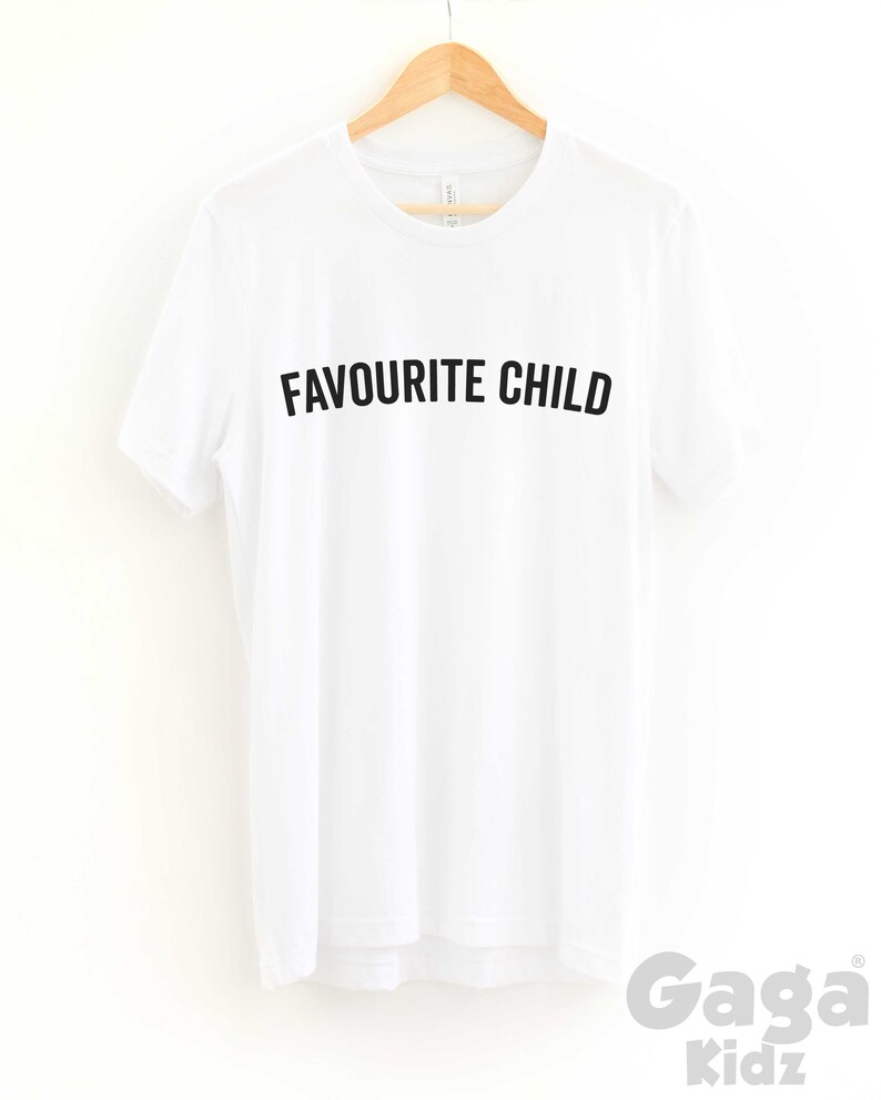 May include: White t-shirt with black text that reads "Favourite Child" on a white hanger. The text is in all caps.