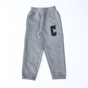 May include: Grey sweatpants with a black letter C on the right leg.