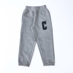 May include: Gray sweatpants with a black letter C on the right leg.