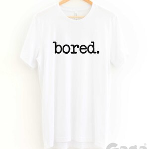 May include: White t-shirt with black text that reads "bored."