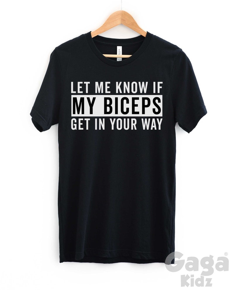 May include: Black t-shirt with white text that reads "Let me know if my biceps get in your way".