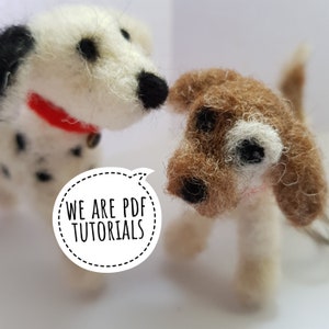 May include: Two needle felted dog figurines, one white with black spots and a red collar, the other brown with white markings. The white dog is looking at the brown dog. The text "WE ARE PDF TUTORIALS" is in a speech bubble.