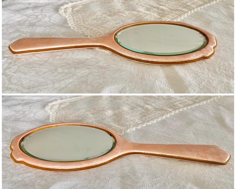 May include: Two vintage oval hand mirrors with pink plastic handles and silver-toned glass mirrors.