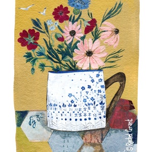 May include: A white ceramic mug with a blue floral pattern and a brown handle, filled with a bouquet of pink, red, and blue flowers. The mug is sitting on a yellow background with a blue and brown patterned surface.