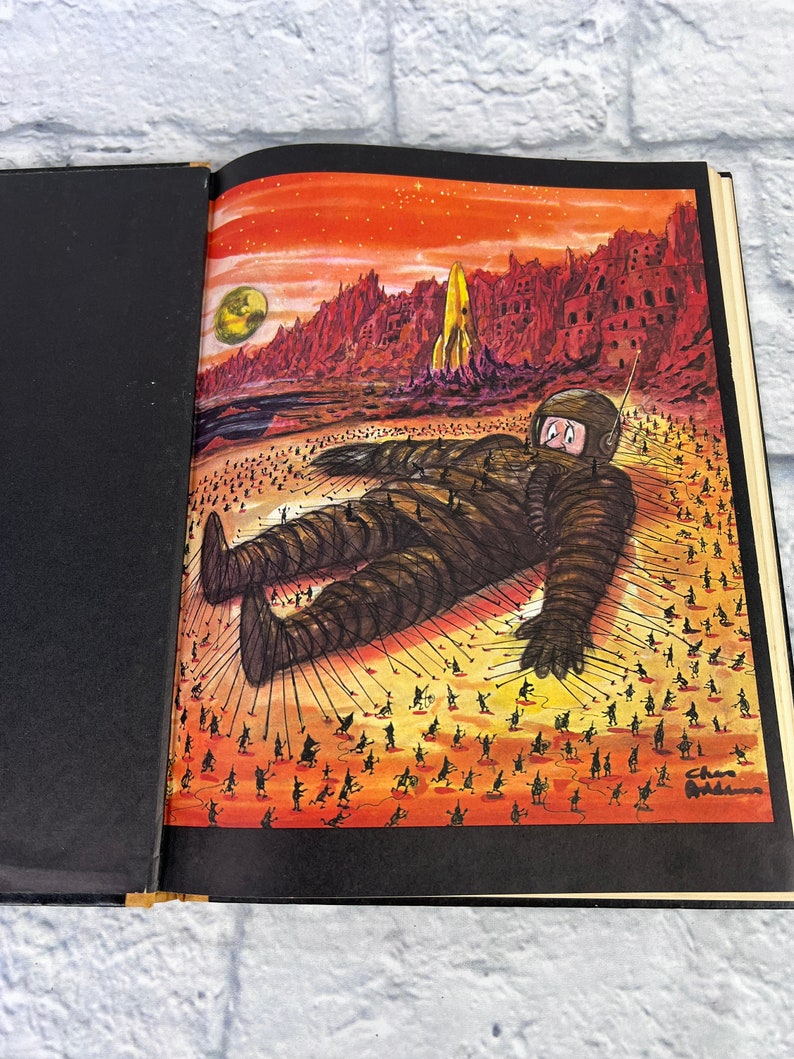 May include: A vintage illustration of a giant astronaut lying on a red and orange desert landscape. Tiny figures are pulling on ropes attached to the astronaut's body. The illustration is signed "Chas Addams".