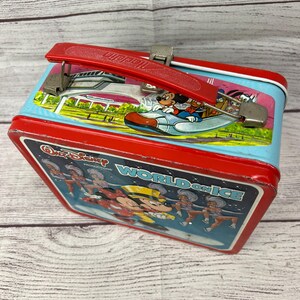 May include: Red metal lunchbox with a blue and white image of Mickey Mouse on ice skates with the text "Walt Disney Productions World on Ice".