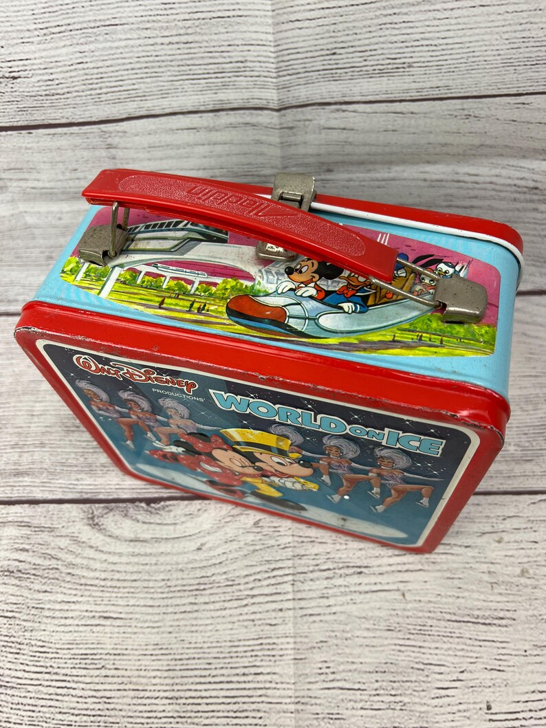 May include: Red metal lunchbox with a blue and white image of Mickey Mouse on ice skates with the text "Walt Disney Productions World on Ice".
