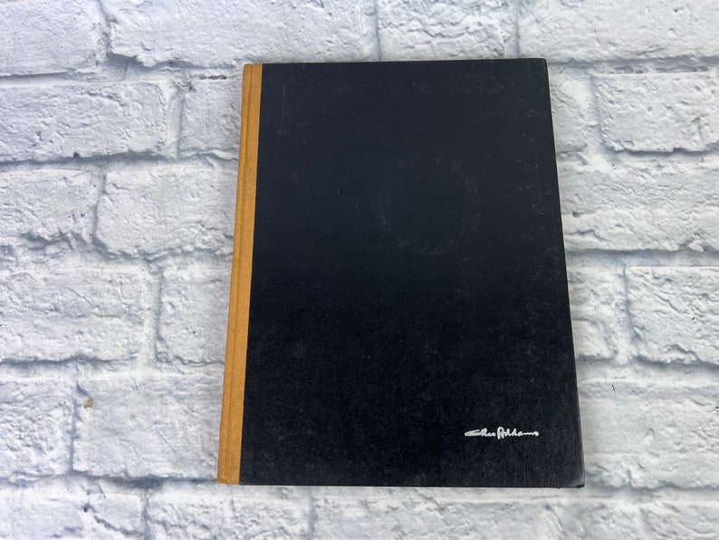 May include: A black hardcover book with a gold spine. The book has a white signature on the front cover that reads "Alan Alda".