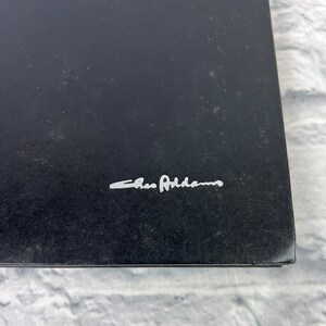 May include: A black book with the signature "Chris Adams" in silver lettering.