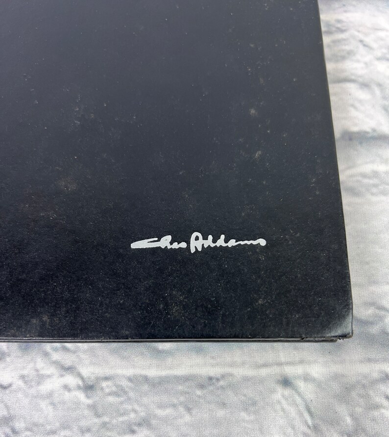 May include: A black book with the signature "Chris Adams" in silver lettering.
