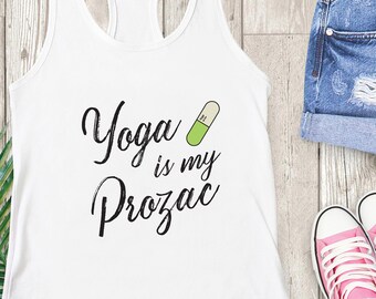 May include: White tank top with the text "Yoga is my Prozac" and a green and white pill graphic. The tank top is paired with denim shorts and pink sneakers.
