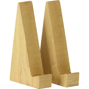 May include: Two wooden display stands made of light brown wood. The stands are triangular in shape and have a small ledge at the top to hold items.