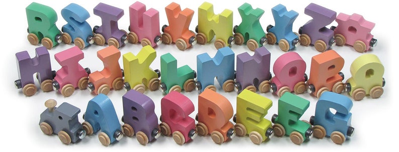K&ouml;nnte beinhalten: Ein Set aus bunten Holzz&uuml;gen in Form von Buchstaben des Alphabets. Jeder Zug hat eine andere Farbe und einen anderen Buchstaben und sie sind alle in alphabetischer Reihenfolge angeordnet. Die Z&uuml;ge sind aus Holz und haben eine glatte, lackierte Oberfl&auml;che.
