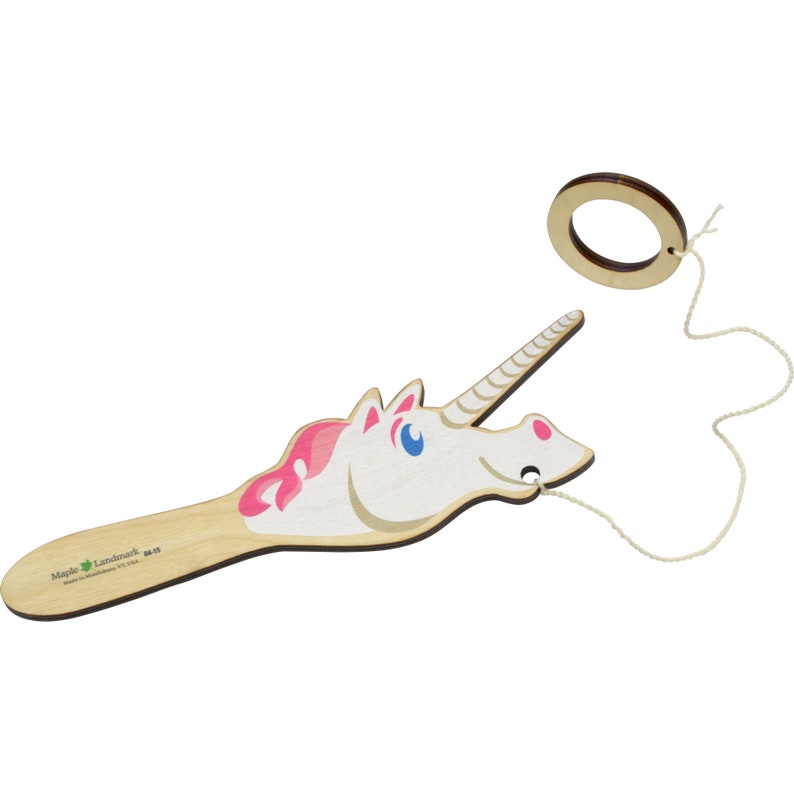Puede incluir: Un juguete de madera con forma de cabeza de unicornio con una crin rosa y ojos azules. El unicornio est&aacute; unido a una cuerda con un anillo de madera en el extremo. El juguete est&aacute; hecho por Maple Landmark.