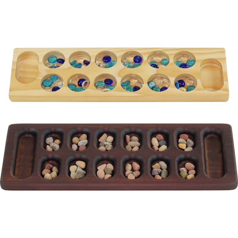 May include: Two wooden game boards for playing Mancala. The top board is light wood with clear glass marbles. The bottom board is dark wood with small brown stones.