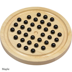 May include: A wooden game board with a circular playing surface and a central hole. The board is made of maple wood and has 42 black marbles arranged in a circular pattern.
