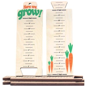 May include: Wooden growth chart with the text "Here we grow!" in green. The chart measures up to 6 feet and features carrots with green tops. Includes wooden base pieces for stability.