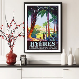 May include: A vintage travel poster advertising the French city of Hy&egrave;res, featuring a colourful illustration of palm trees, a town nestled in the hills, and people walking along a path. The text reads "Hy&egrave;res et ses &icirc;les (Porquerolles et Port-Gros) La station la plus au sud de la C&ocirc;te d'Azur."