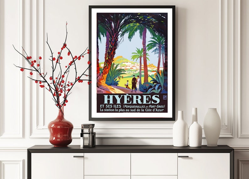 May include: A vintage travel poster advertising the French city of Hy&egrave;res, featuring a colourful illustration of palm trees, a town nestled in the hills, and people walking along a path. The text reads "Hy&egrave;res et ses &icirc;les (Porquerolles et Port-Gros) La station la plus au sud de la C&ocirc;te d'Azur."