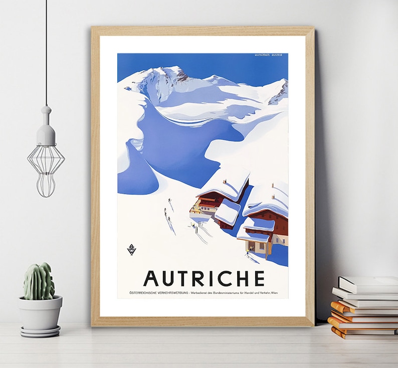 May include: A vintage travel poster advertising Austria. The poster features a snowy mountain scene with a blue sky and two small buildings. The text "AUTRICHE" is printed in black at the bottom of the poster.