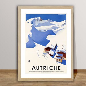 May include: A vintage travel poster advertising Austria. The poster features a snowy mountain scene with a blue sky and a small village of red-roofed houses. The text "AUTRICHE" is printed in black at the bottom of the poster.