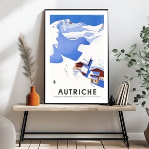 May include: A vintage travel poster with a blue and white illustration of a snowy mountain range and a small village. The poster has the word "AUTRICHE" in bold, black letters at the bottom.