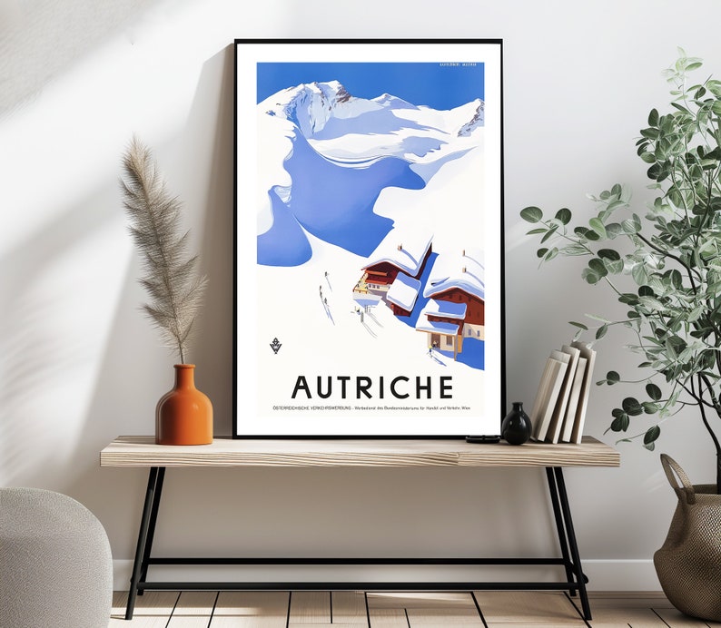 May include: A vintage travel poster with a blue and white illustration of a snowy mountain range and a small village. The poster has the word "AUTRICHE" in bold, black letters at the bottom.