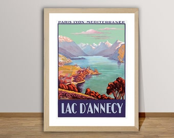 May include: A vintage travel poster advertising a trip to Lac d'Annecy in the French Alps. The poster features a scenic view of the lake and mountains with a blue sky and white clouds. The text on the poster reads "Paris-Lyon-Mediterranee Lac d'Annecy".