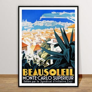 May include: A framed vintage travel poster for Beausoleil, Monte-Carlo Sup&eacute;rieur. The poster features a cityscape with orange rooftops, white buildings, and a blue sky. Large dark green leaves are in the foreground, with text at the bottom.
