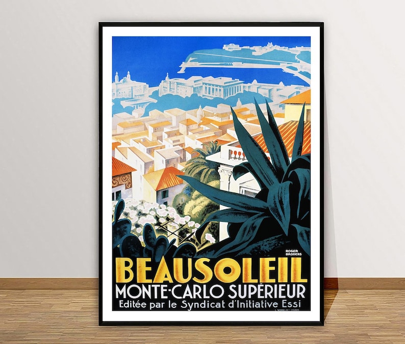 May include: A framed vintage travel poster for Beausoleil, Monte-Carlo Sup&eacute;rieur. The poster features a cityscape with orange rooftops, white buildings, and a blue sky. Large dark green leaves are in the foreground, with text at the bottom.